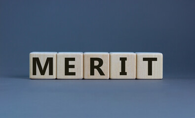 Merit symbol. Wooden cubes with the word 'merit'. Beautiful grey background, copy space. Business...