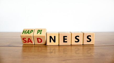 Happiness or sadness symbol. Turned cubes and changed the word 'sadness' to 'happiness'. Beautiful wooden table, white background. Business, psychological and happines or sadness concept. Copy space.