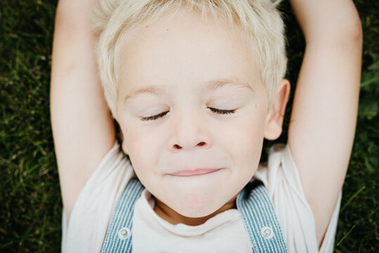 sweet blond toddler boy lying on the grass outdoors