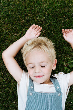 sweet blond toddler boy lying on the grass outdoors