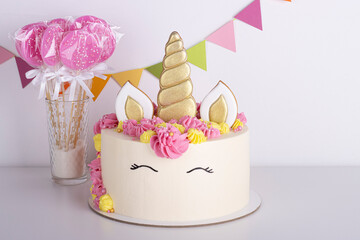 white delicate unicorn cake with pink lollipops on a white background