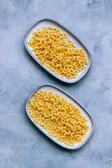 Wheat raw Italian pasta in plates isolated on blue background.