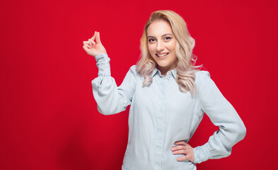 Young woman snapping fingers, isolated on red background. One cute girl gesturing click