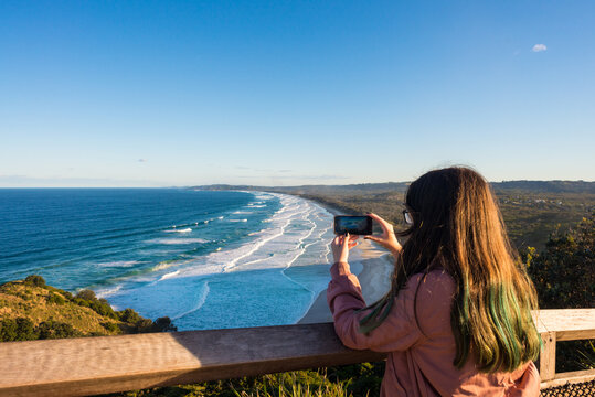 teen taking photo of scenic coastline