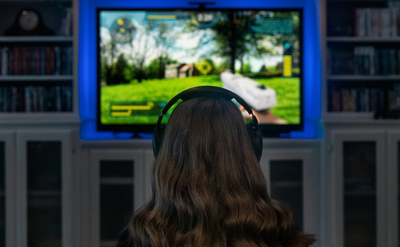 Rear View Of Young Woman Playing Shooter Video Game