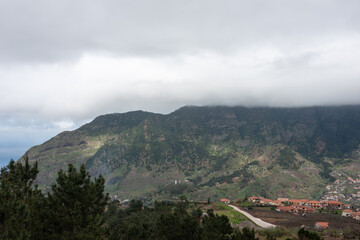 Fototapeta na wymiar Typical landscape of Madeira Island. View on Sao Vicente valley with high mountians hidden in the clouds. Selective focus. 