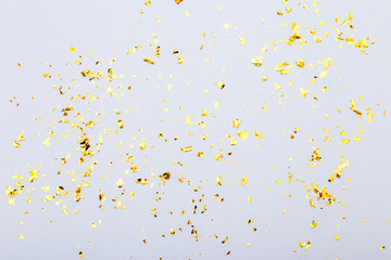 Golden confetti on the gray background. Holiday background, top view