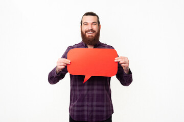 Cheerful man with beard in shirt holding red empty speech bubble