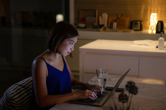 Woman working from home at night - looking at illuminated screen