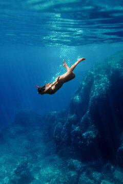 Woman diving in clear sea near a rock