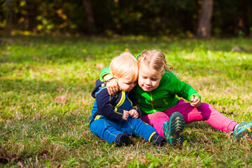 Naklejka na ściany i meble The cheerful girl is hugging her crying brother outdoor