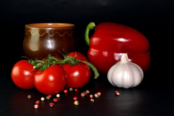 branch of cherry tomatoes, red paprika, garlic and spice on a black background