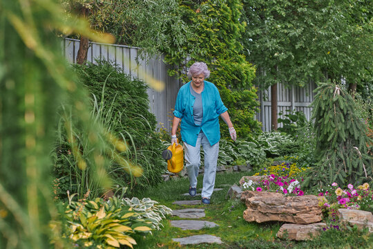 Beautiful elderly woman caring for plants in her garden