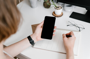 Busy person with smartphone writing in planner