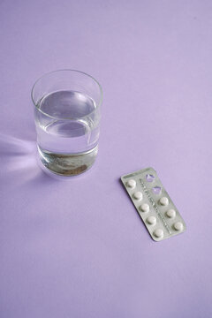 Pack of pills next to a glass of water