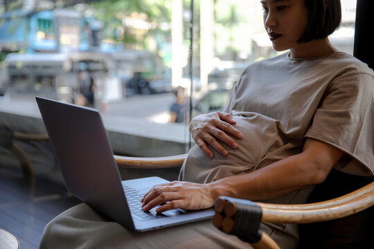 Pregnant woman working on a computer from outdoor co-working space