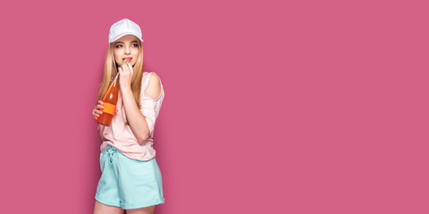 Obraz premium Sporty woman with cold drink standing on pink background
