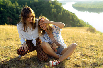 two hippie girlfriends have a rest on the green lawn