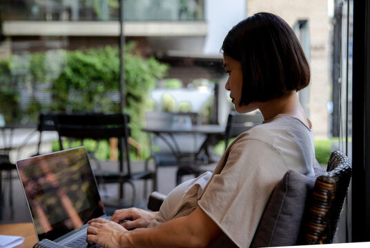 Pregnant woman working on a computer from outdoor co-working space