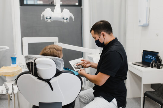Asian dentist showing X ray scan to patient