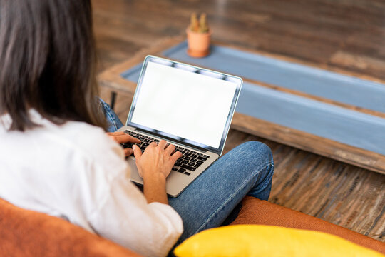 Back view of focused female freelancer working on laptop from home office
