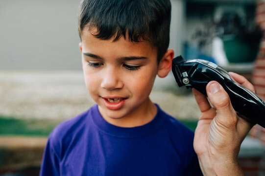 Young boy getting his hair cut with clippers.