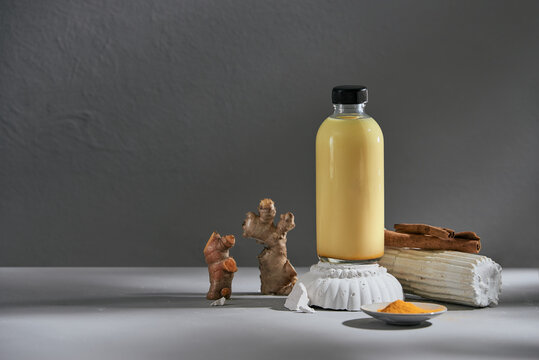 Golden milk in a glass bottle and turmeric root, cinnamon stick and star anise on a serving tray