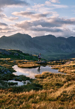 Female walker on Hard Knott looking towards Sca Fell at sunset. Lake District, Cumbria, UK.