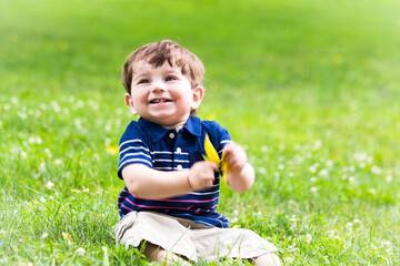 little boy playing with a leaf in the grass