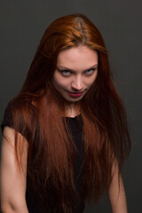 Naklejka premium studio portrait of a young red-haired woman in black clothes