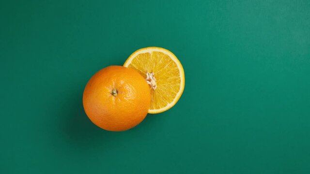orange rolls in the center of the frame, splits in half and becomes a glass of juice. stop motion animation