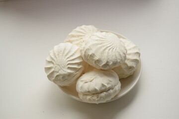 Five white marshmallows lie on a white plate on a white background