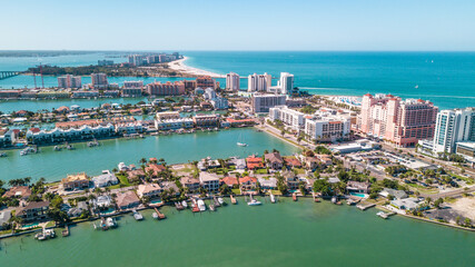 Fototapeta na wymiar Spring break or Summer vacations in Florida. Ocean beach and Resorts in US. Blue-turquoise color water. American Coast or shore. Island in Gulf of Mexico. Clearwater Beach FL. Aerial view of city.