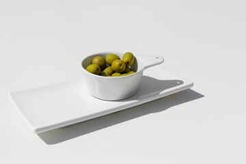 Bowl of green olives on white background. Benefits of the mediterranean diet.