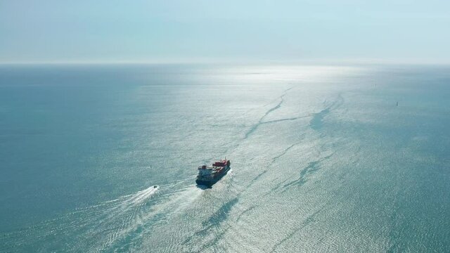 A ship hovering above the surface of the sea. Aerial footage of two vessels floating across immense blue ocean. 