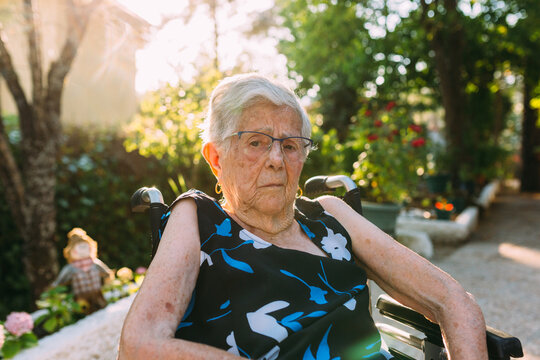 Elderly woman sitting outdoor on wheelchair at sunset