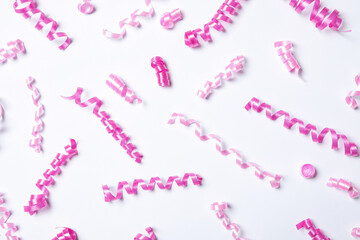 Pink serpentine streamers on white background, top view