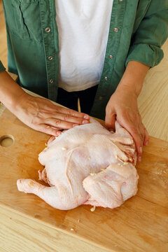 Crop person spreading garlic on chicken