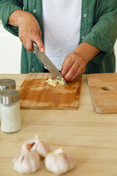 Crop person chopping garlic on table