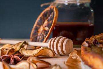 Still life with homemade organic food. Pear pie, jar with honey and dipper, cinnamon, dried fruits,...