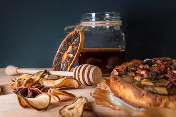 Still life with homemade organic food. Pear pie, jar with honey and dipper, cinnamon, dried fruits,...