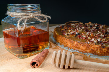 Still life with homemade organic food. Pear pie, jar with honey and dipper, cinnamon, dried fruits,...