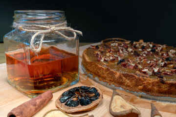 Still life with homemade organic food. Pear pie, jar with honey and dipper, cinnamon, dried fruits, nuts. Healthy breakfast without added sugar.