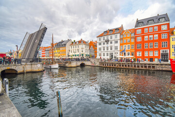 The Nyhavn bridge opens to let a small sailboat through the canal in the waterfront tourist area of Nyhavn in Copenhagen, Denmark.