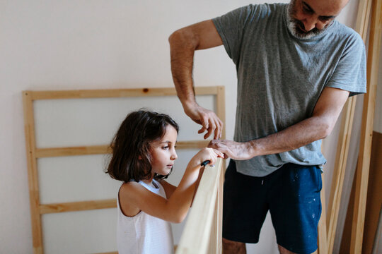 Kid helping her father assembling a furniture.