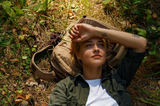 Female traveler resting on backpack in forest