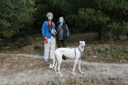 Elderly Man and woman with facemark and dog outdoors