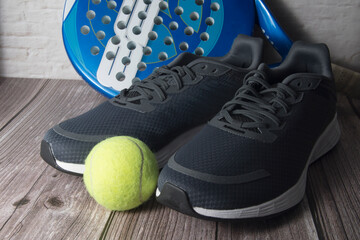 Indumentaria deportiva para jugar al pádel.  Un par de zapatillas, pelota y pala para competir.