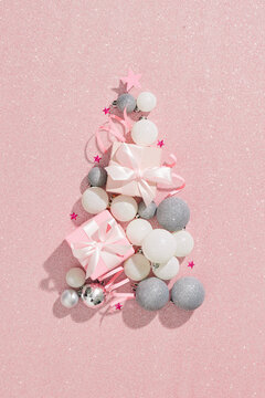 Christmas presents. Xmas balls white, silver color, in a tree shape and gift boxes against pastel pink background