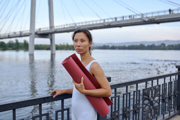 asian woman does street yoga in a Park by the river in summer